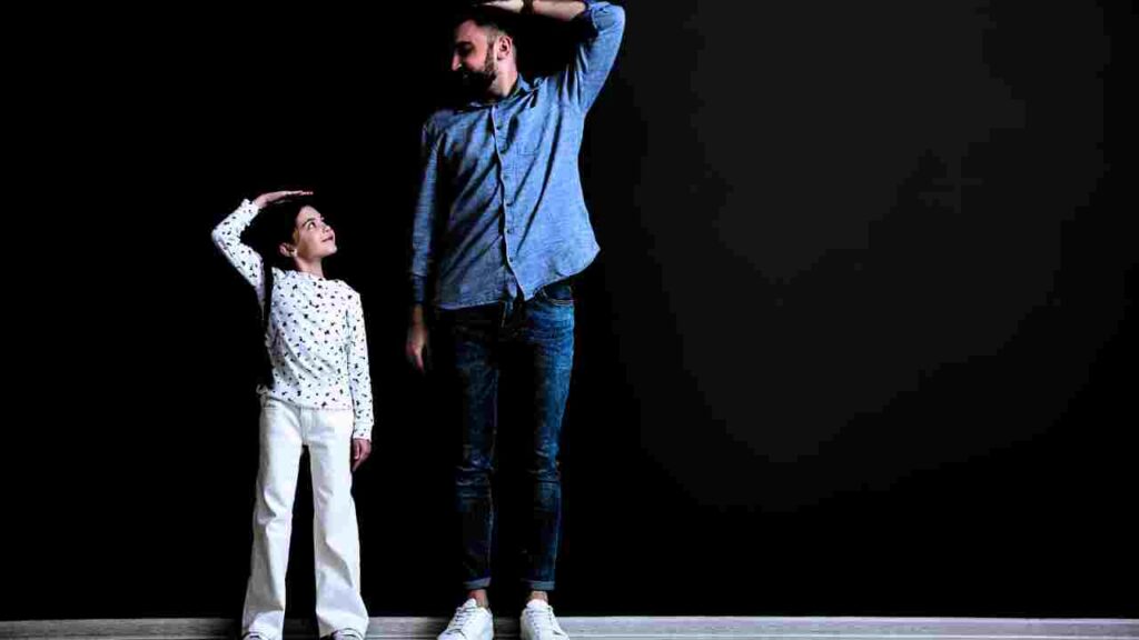 a man and a girl standing in front of a black wall